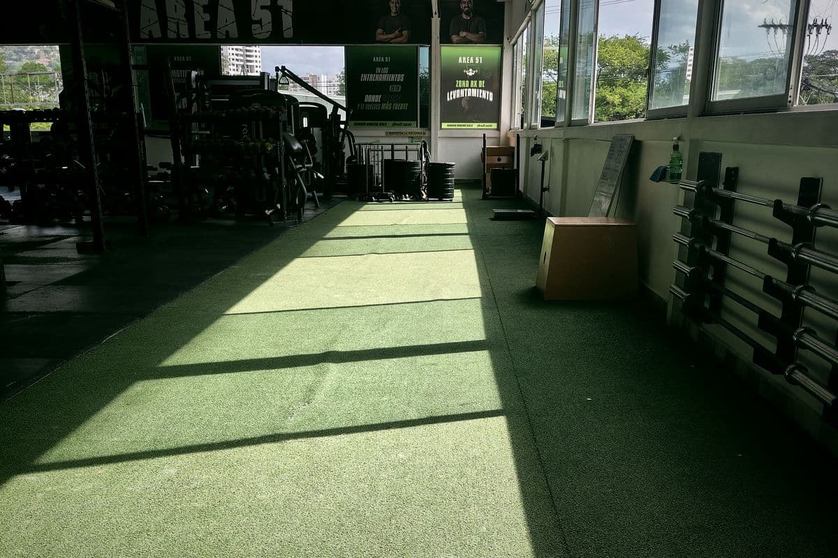 Espacio abierto con grama sintética y barras en la pared